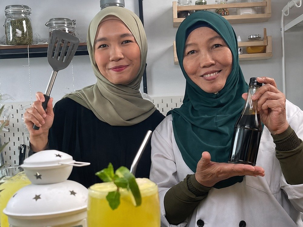 Two iCookAsia hosts preparing a recipe together in the kitchen studio