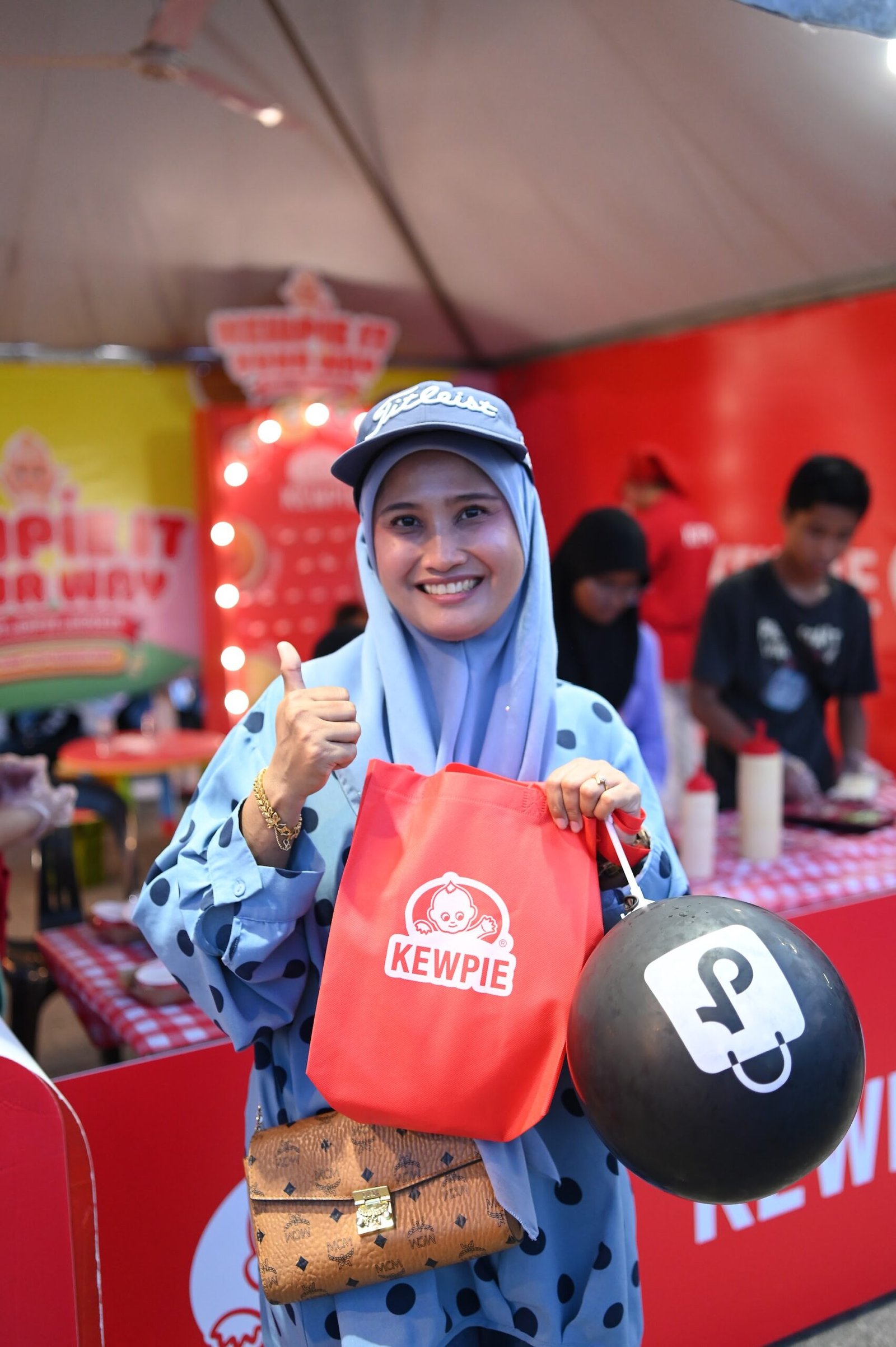 Carnival visitor tasting a KEWPIE mayo sampling portion