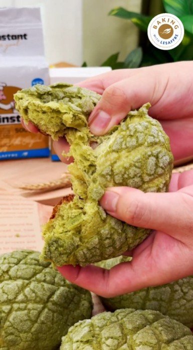 Hands tearing a matcha melon pan with Saf-instant yeast in the background